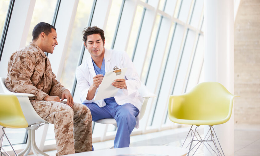 VA Doctor talking to Veteran in Camo in Waiting Room